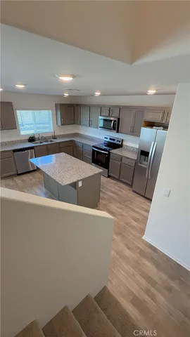 a kitchen with stainless steel appliances kitchen island granite countertop a sink and white cabinets