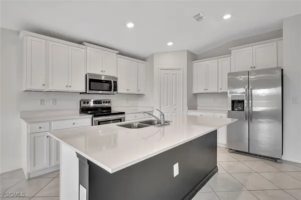 a kitchen with kitchen island a sink a stove a refrigerator and white cabinets