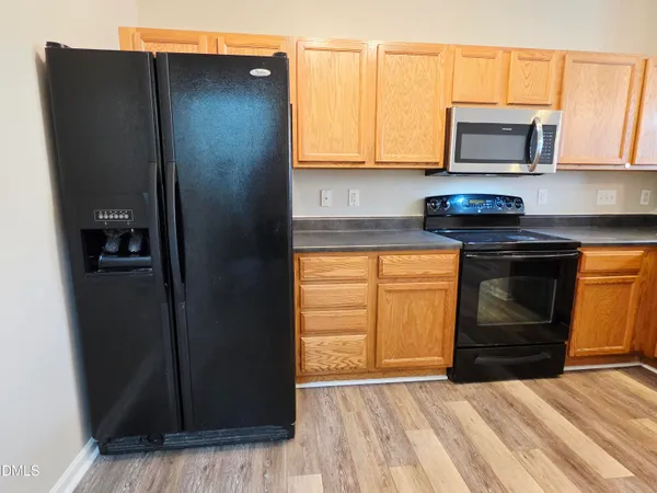 a kitchen with granite countertop a stove and a microwave with cabinets