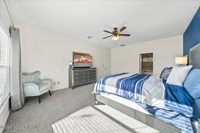 a spacious bedroom with a bed a couch and a chandelier