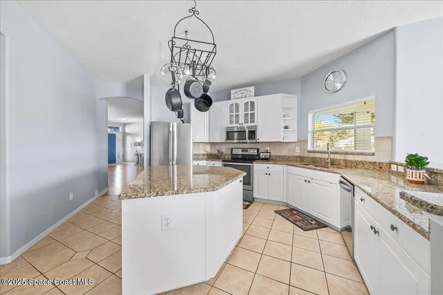 a kitchen with stainless steel appliances granite countertop a sink a stove cabinets dining table and chairs