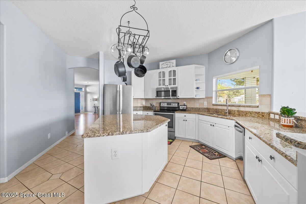 7469 Hackberry Road Cocoa, FL 32927 - Photo 8 of 27 a kitchen with stainless steel appliances granite countertop a sink a stove cabinets dining table and chairs