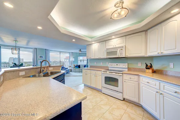 a kitchen with stainless steel appliances granite countertop a sink dishwasher stove and white cabinets with wooden floor