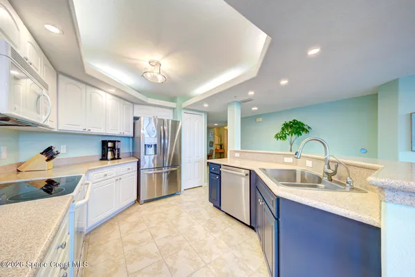 a large kitchen with a stove a sink a refrigerator and cabinets