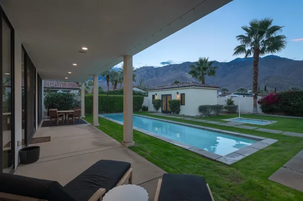 a view of a patio with table and chairs potted plants and palm tree
