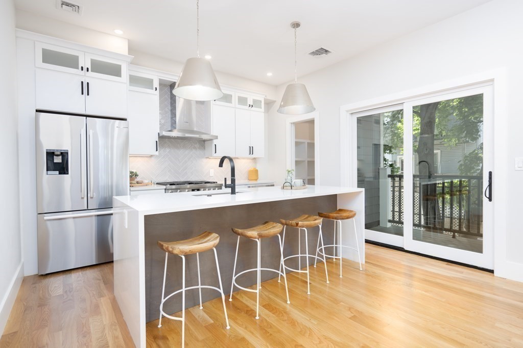 10 Hardan Road, Unit 10 Somerville, MA 02144 - Photo 5 of 22 a kitchen with stainless steel appliances granite countertop a refrigerator a stove a sink dishwasher and white cabinets with wooden floor