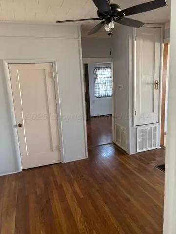 a view of empty room with wooden floor and fan