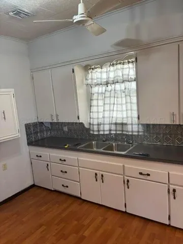 a kitchen with granite countertop a sink and a white cabinets