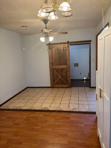a view of an empty room with wooden floor and chandelier