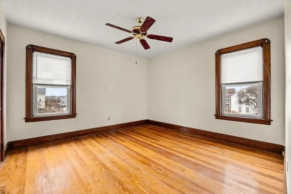 a view of empty room with wooden floor and fan