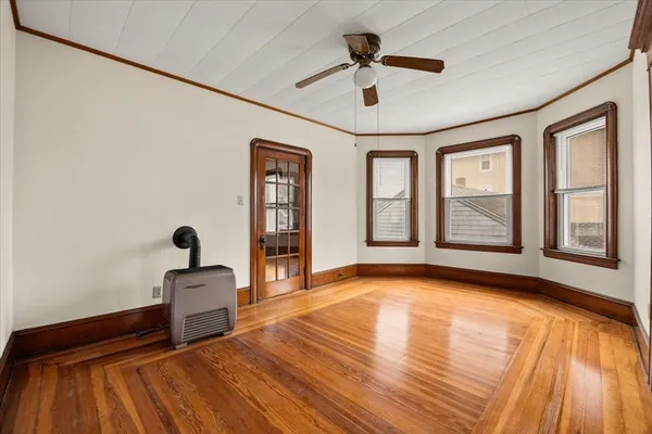 a view of an empty room with a window and wooden floor