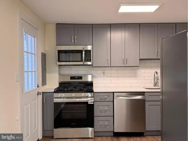 a kitchen with cabinets stainless steel appliances and wooden floor