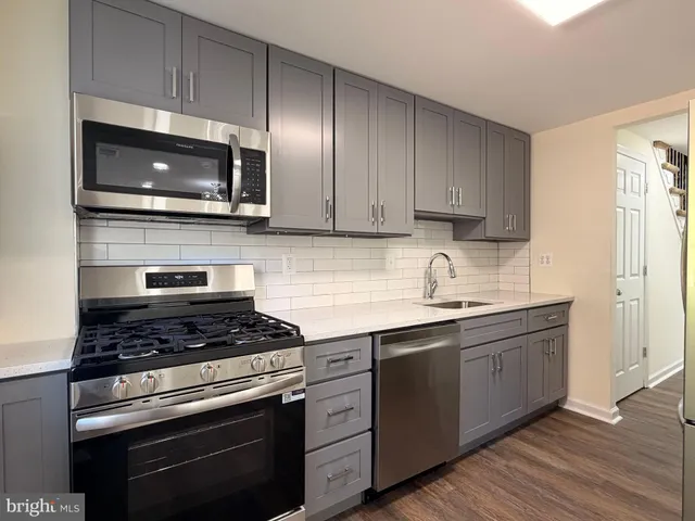 a kitchen with cabinets stainless steel appliances and wooden floor