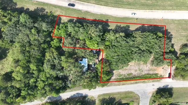 an aerial view of residential houses with outdoor space and trees