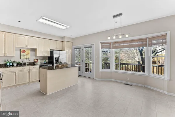 a kitchen with stainless steel appliances kitchen island granite countertop a stove top oven a refrigerator a sink and dishwasher with white cabinets