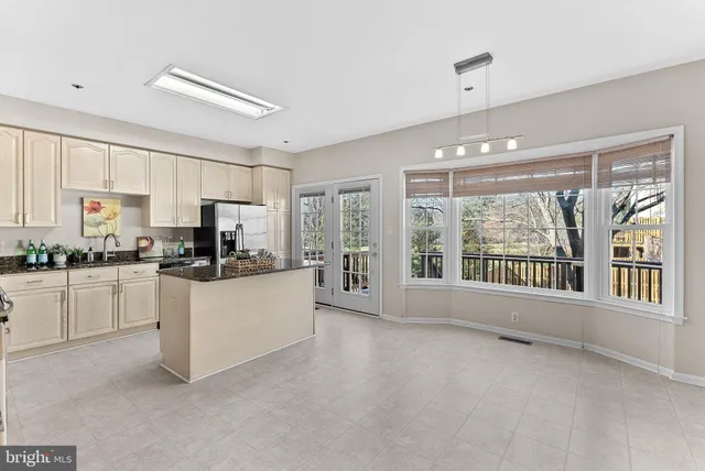 a kitchen with stainless steel appliances kitchen island granite countertop a stove top oven a refrigerator a sink and dishwasher with white cabinets