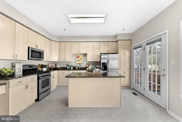 a kitchen with stainless steel appliances granite countertop a stove a sink and white cabinets