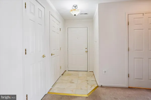 an empty room with chandelier fan and windows