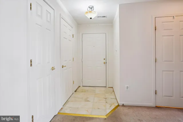 an empty room with chandelier fan and windows