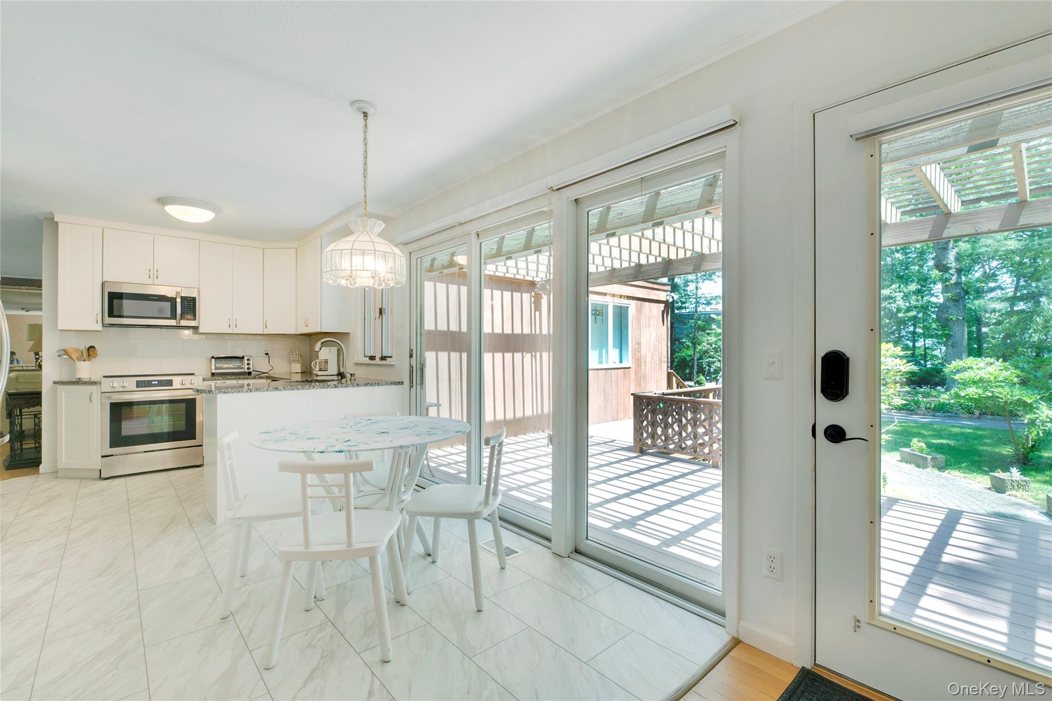 1075 Inlet Lane Greenport, NY 11944 - Photo 3 of 30 a kitchen with stainless steel appliances granite countertop a stove top oven a sink with a dining table and chairs