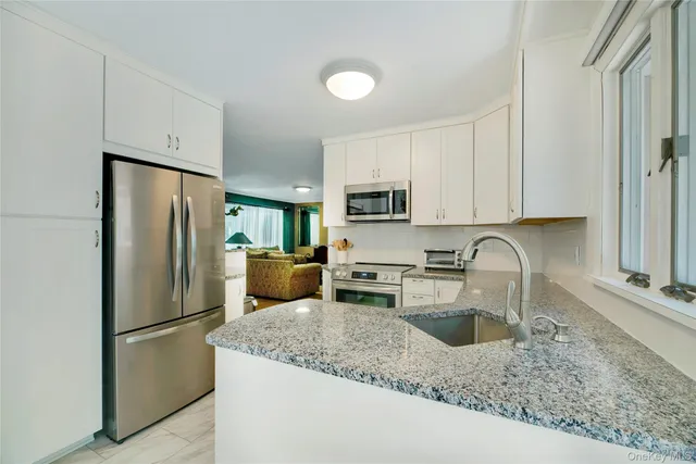 a kitchen with stainless steel appliances granite countertop a refrigerator a stove a sink a stove a oven with white cabinets