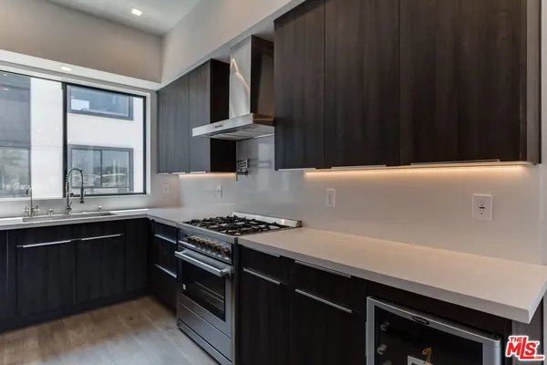 a kitchen with kitchen island a counter top space wooden floor and a refrigerator