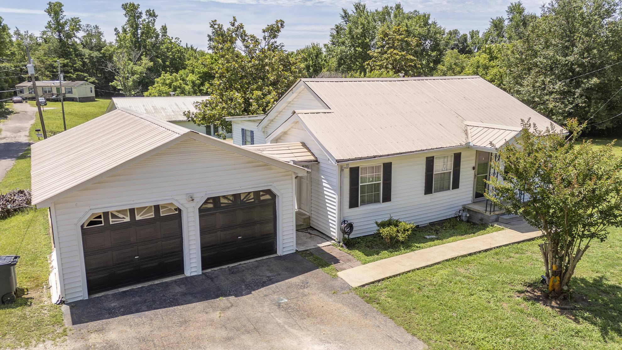 369 Bethel-Purdy Road Bethel Springs, TN 38315 - Photo 2 of 19 Two-car garage with black paneled doors, white siding, and a metal roof