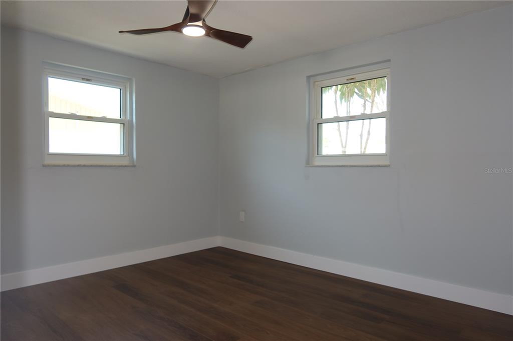 7521 Coventry Drive Port Richey, FL 34668 - Photo 24 of 45 an empty room with wooden floor ceiling fan and windows