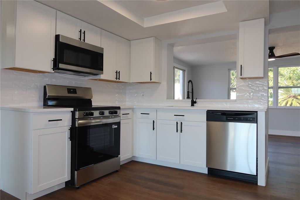 7521 Coventry Drive Port Richey, FL 34668 - Photo 7 of 45 a kitchen with stainless steel appliances kitchen island granite countertop a stove a sink and a microwave