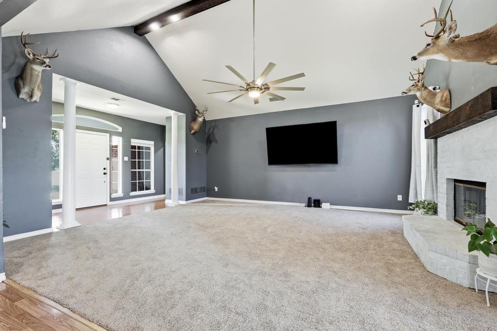1328 Pierce Road Red Oak, TX 75154 - Photo 9 of 40 Spacious living area featuring a vaulted ceiling with exposed wood beam, a contemporary ceiling fan, and a built-in fireplace