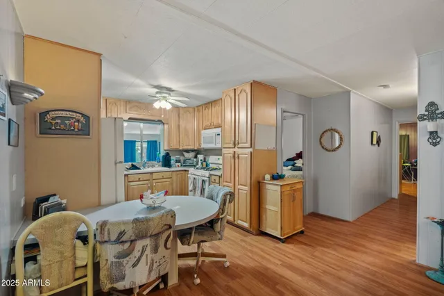 a kitchen with stainless steel appliances granite countertop a dining table chairs refrigerator and sink