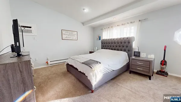 a bedroom with a bed and a flat tv screen on the dresser