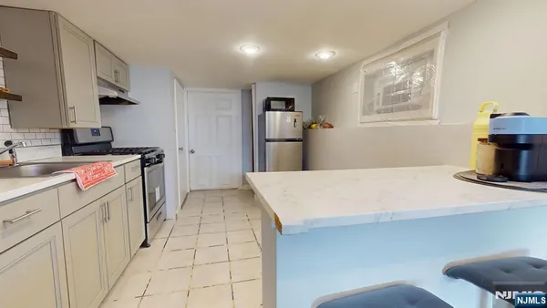 a room with kitchen island a sink a stove a refrigerator and cabinets