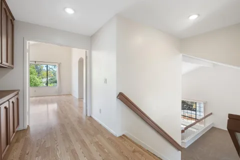 a view of a hallway with wooden floor and stairs