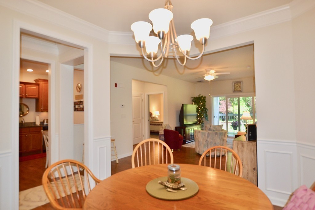 7 Augustus Court, Unit 1013 Reading, MA 01867 - Photo 17 of 34 a dining room with wooden floor a chandelier a wooden table and chairs