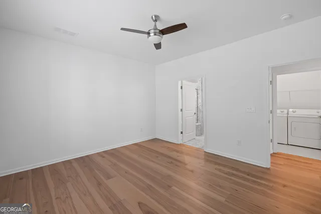 an empty room with wooden floor and ceiling fan