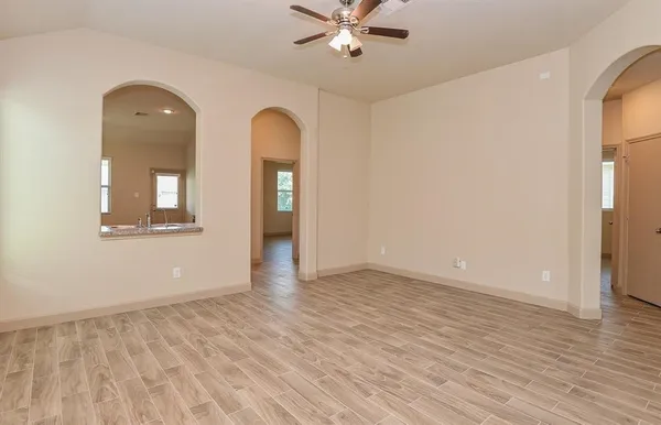 a view of an empty room with wooden floor and a window