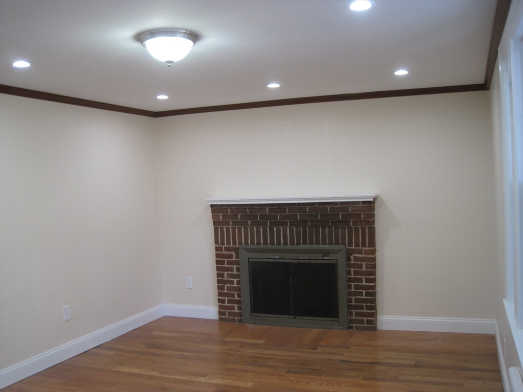 139 Readville Street Boston, MA 02136 - Photo 5 of 31 a view of an empty room with wooden floor and a fireplace