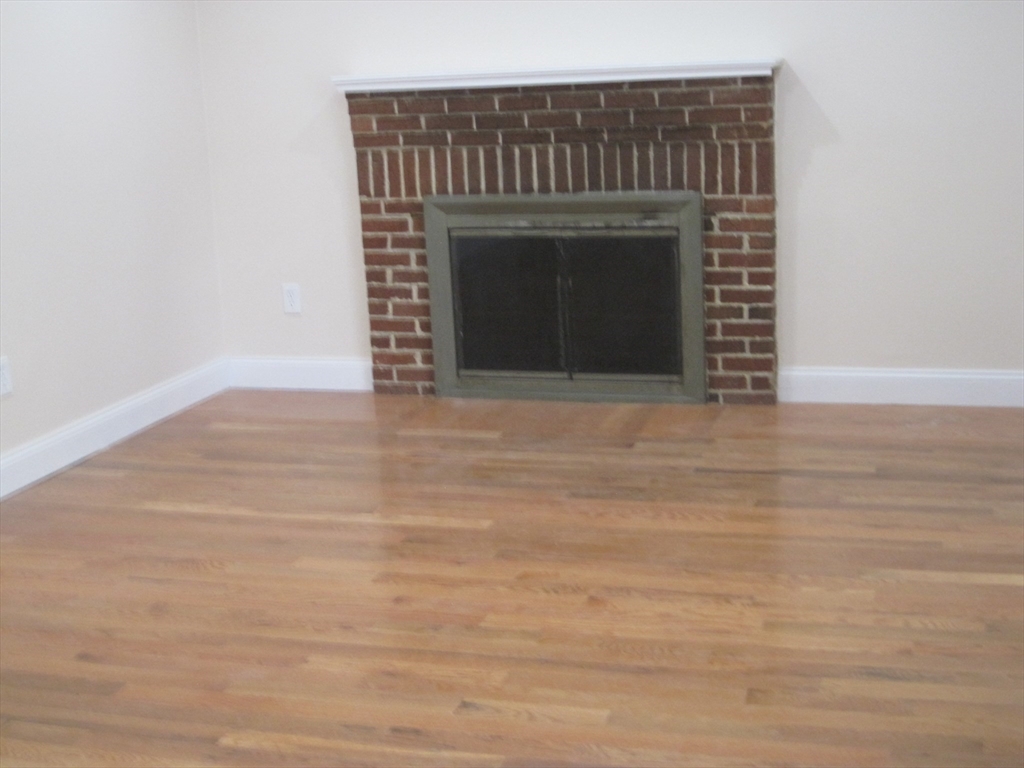 139 Readville Street Boston, MA 02136 - Photo 6 of 31 a view of empty room with wooden floor and fireplace