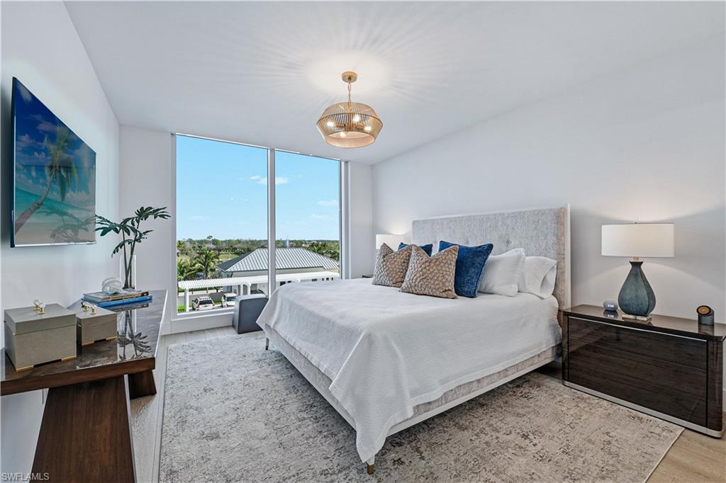 13935 Old Coast Road, Unit 406 Naples, FL 34110 - Photo 15 of 49 Bedroom with wood finished floors and a chandelier