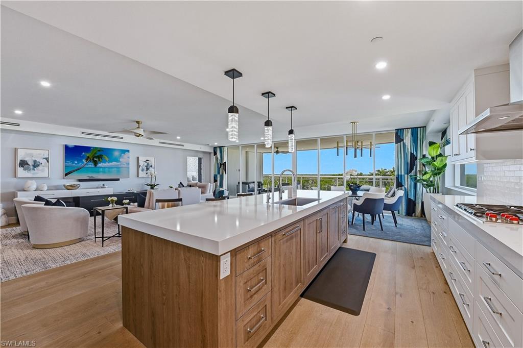 13935 Old Coast Road, Unit 406 Naples, FL 34110 - Photo 49 of 49 Kitchen featuring dual tone cabinetry, open floor plan, light wood finished floors, stainless steel gas stovetop, and a center island with sink
