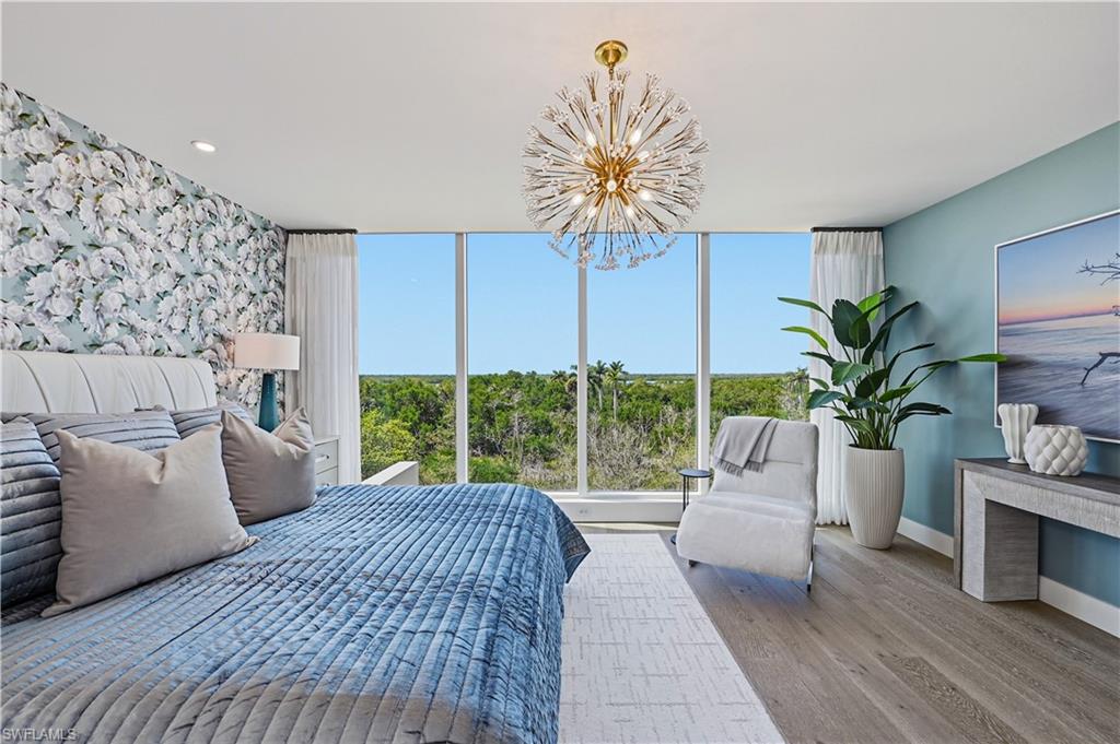 13935 Old Coast Road, Unit 406 Naples, FL 34110 - Photo 22 of 49 Bedroom with light wood-style flooring, hanging lights, and an accent wall