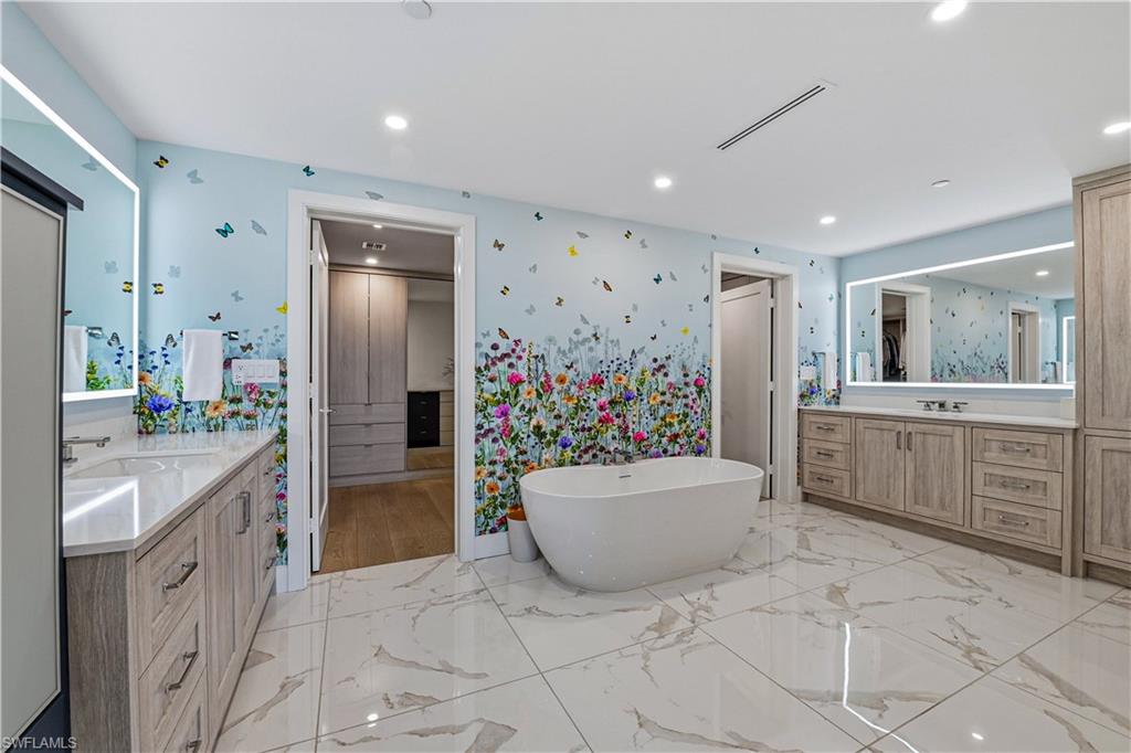 13935 Old Coast Road, Unit 406 Naples, FL 34110 - Photo 23 of 49 Bathroom featuring two vanities, a soaking tub, light marble finish flooring, recessed lighting, and wallpapered walls