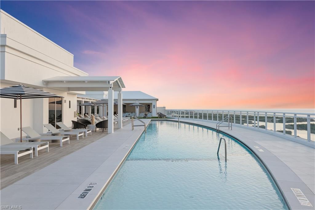 13935 Old Coast Road, Unit 406 Naples, FL 34110 - Photo 33 of 49 Pool at dusk featuring a community pool and a patio