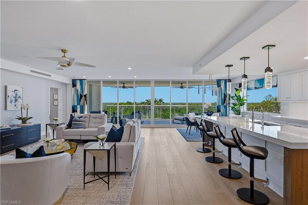 13935 Old Coast Road, Unit 406 Naples, FL 34110 - Photo 5 of 49 Living area featuring light wood-style floors, ceiling fan, healthy amount of natural light, and floor to ceiling windows