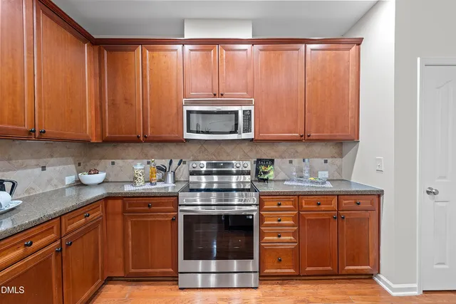 a kitchen with granite countertop wooden cabinets and a stove top oven