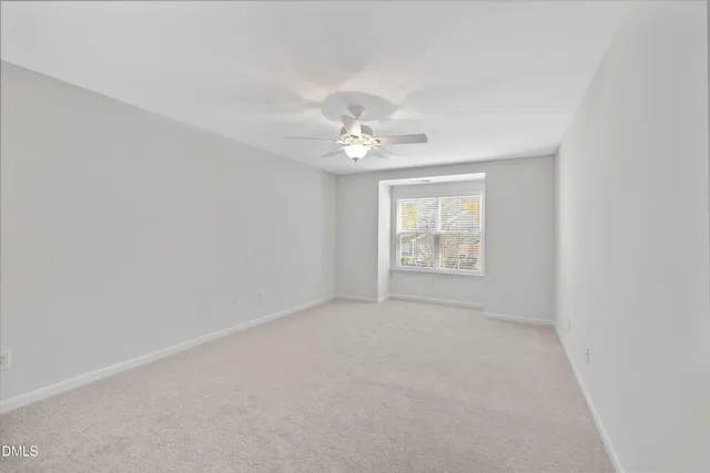 an empty room with windows and ceiling fan