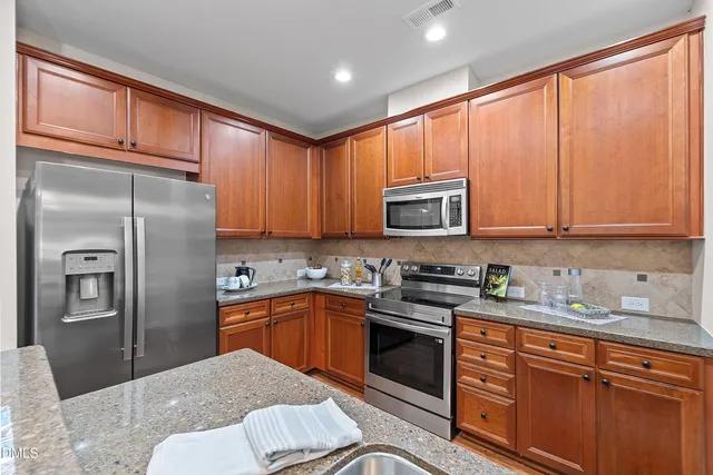 a kitchen with stainless steel appliances granite countertop a refrigerator stove top oven a sink and dishwasher