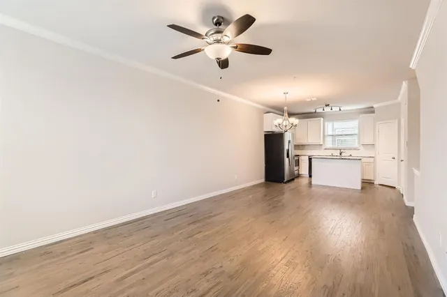 a view of an empty room with a kitchen fan and wooden floor