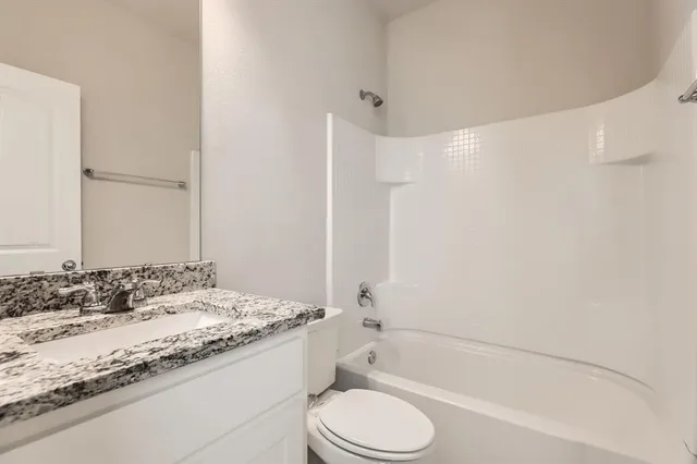 a bathroom with a granite countertop sink toilet mirror and bathtub